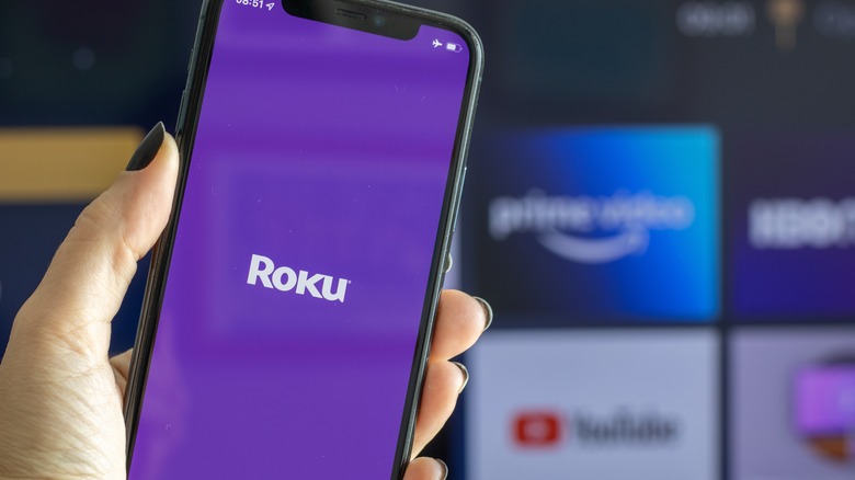 Roku on smartphone by TV screen