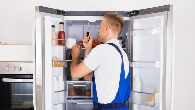 Repairman fixes refrigerator