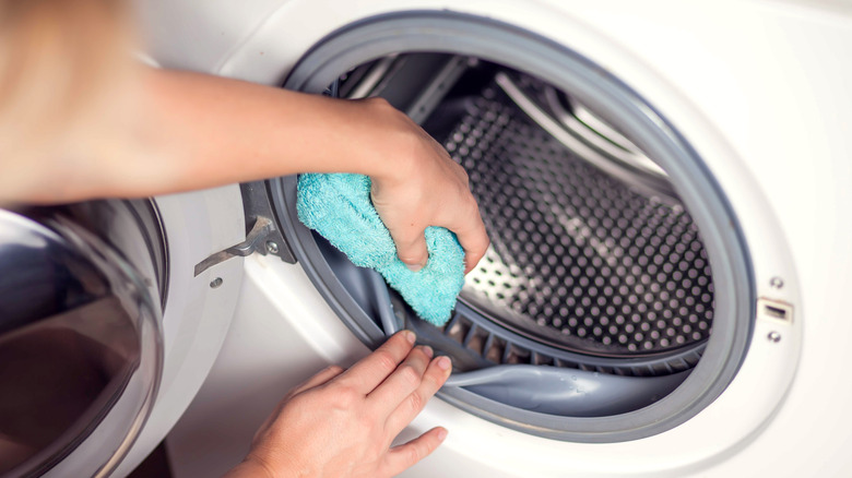 person cleaning washer with rag