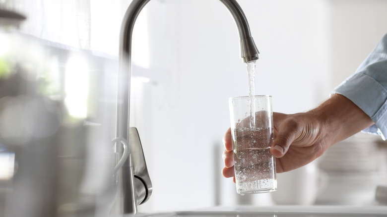 Man filling water glass from a faucet