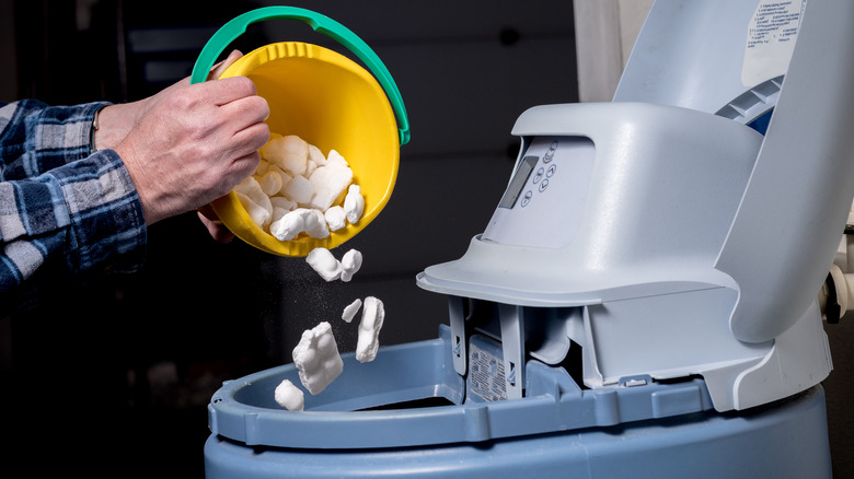 Man filling water softener with salt