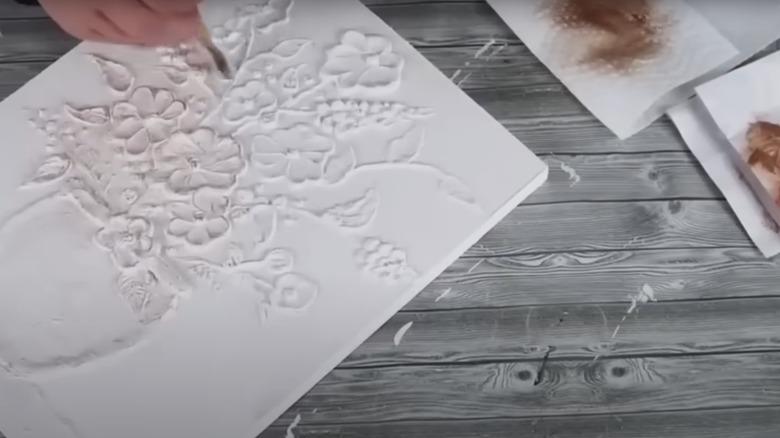 Person creating white textured floral painting