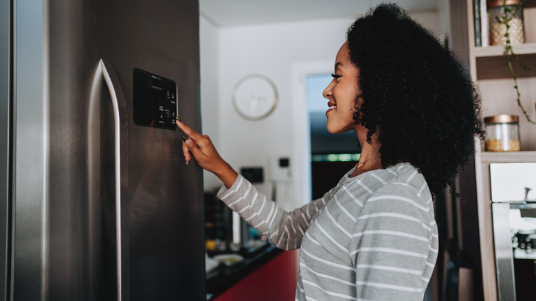 woman using a touchscreen console on her smart fridge