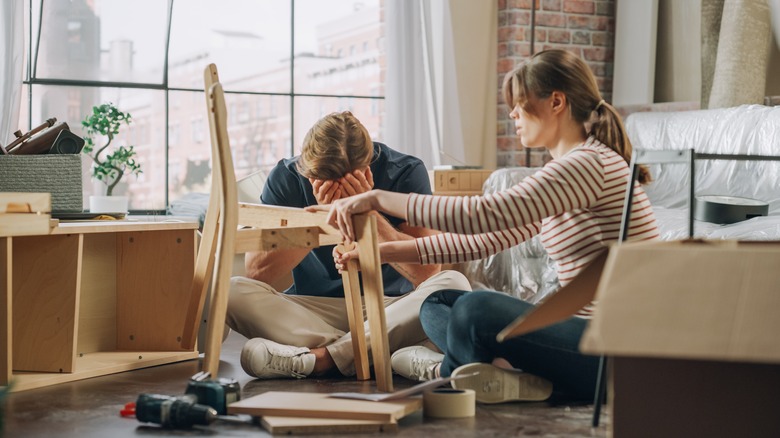 A young couple is frustrated while trying to assemble furniture