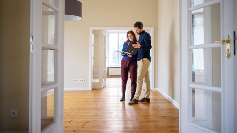 man and woman inspecting a new home while looking through a folder