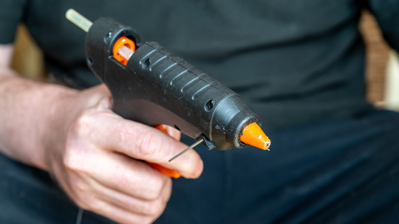 man holding hot glue gun 