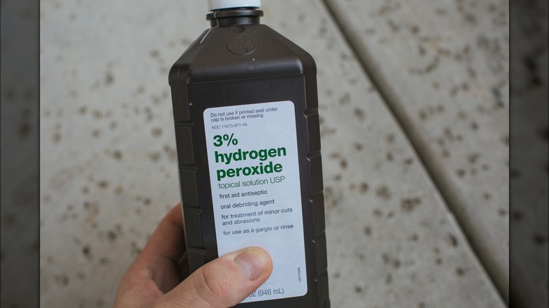Hand holding hydrogen peroxide bottle