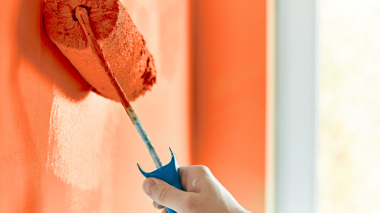 Orange paint roller going up against a wall.