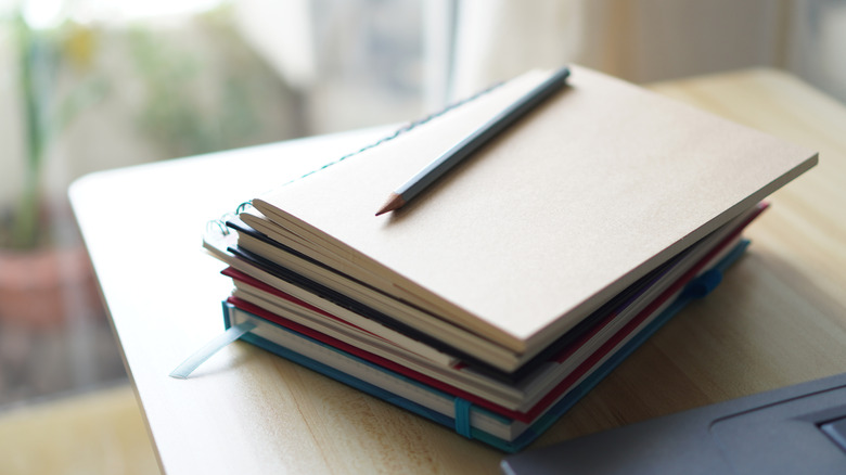 Pile of books on desk with pencil on top