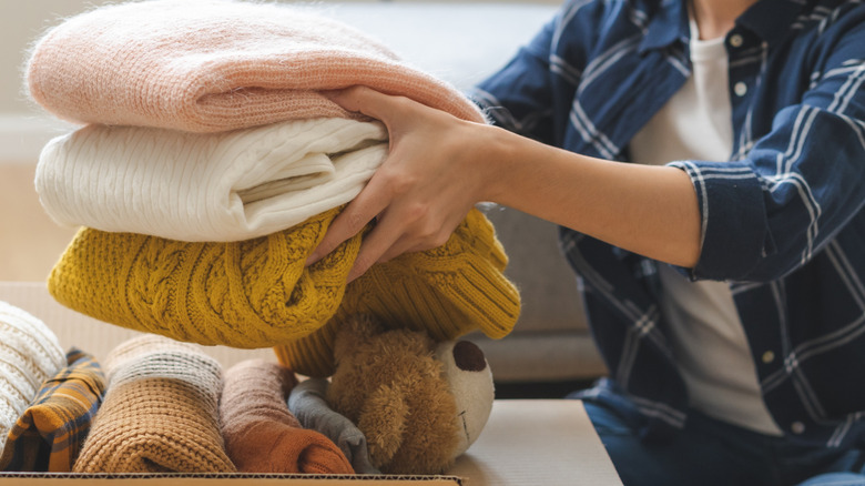 person packing folded sweaters