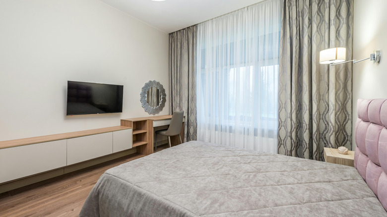 A bedroom with a floating storage cabinet mounted to the wall