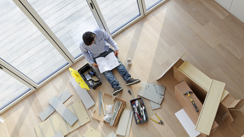 man looking at furniture assembly instructions