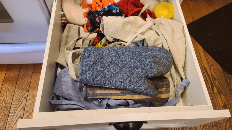 A messy kitchen drawer filled with kitchen fabrics.