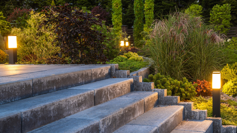 Outdoor path lighting next to stairs and vegetation.