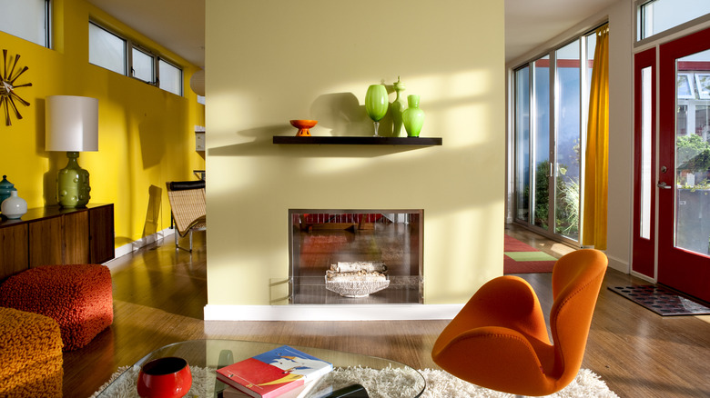 A mid-century modern living room with colorful furniture and a fireplace painted yellow.