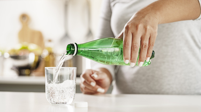 woman pouring soda into cup 