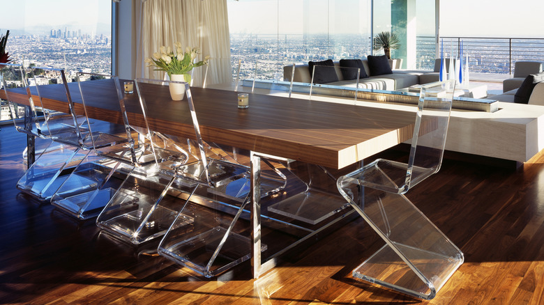 Wood and metal table surrounded by modern Lucite chairs