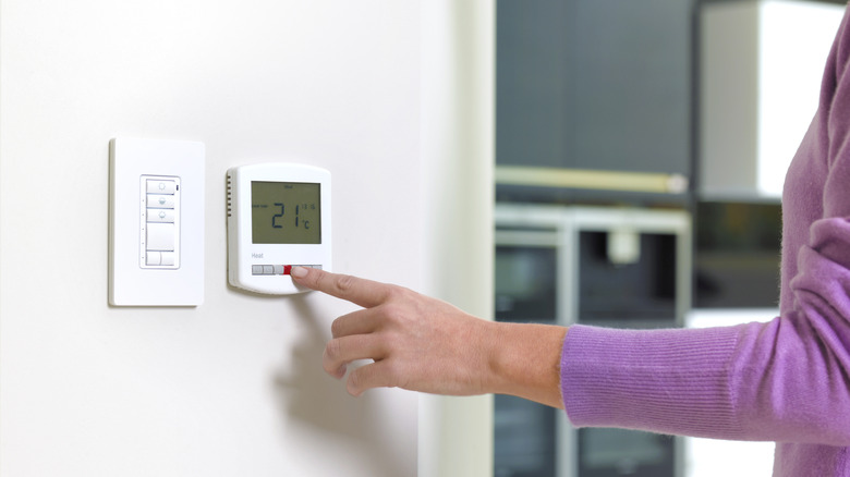 Woman's hand touching thermostat