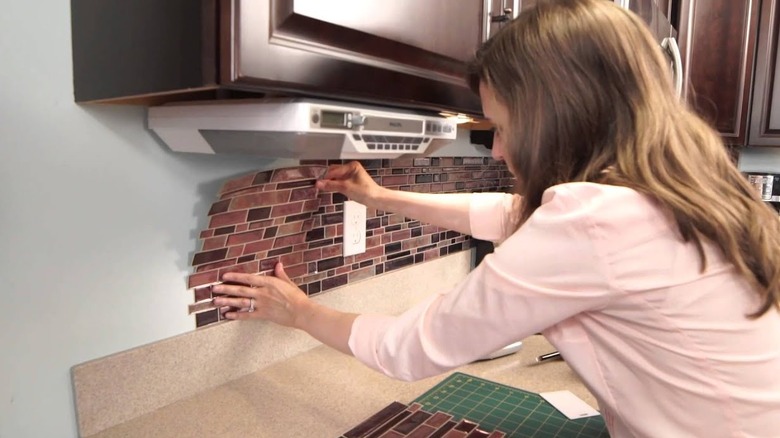 woman Installing peel-and-stick tile