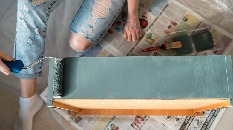 Woman paints dresser drawer 