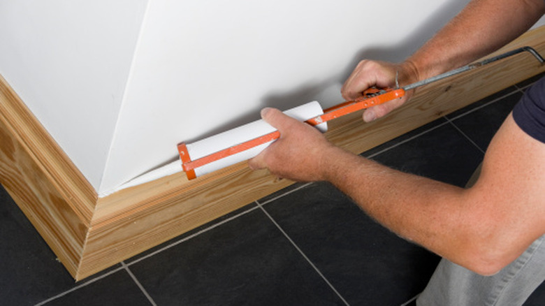 Person installing a wood baseboard