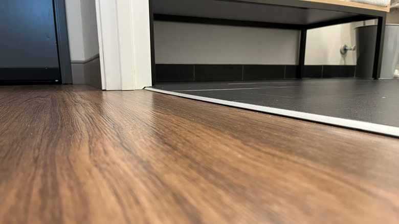 A metal transition strip between wood and tile floors