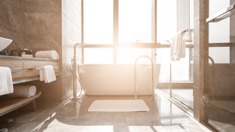 Brightly lit beige bathroom with tub