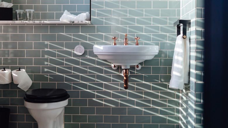 Green tile bathroom with natural light through blinds