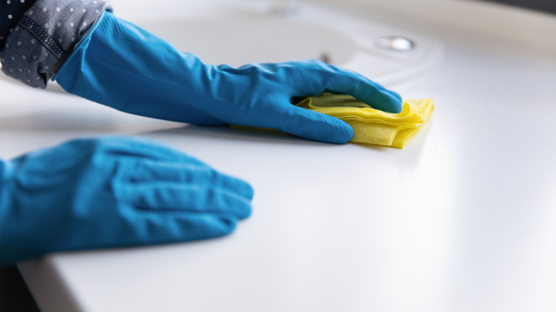 Person wearing gloves and wiping a countertop