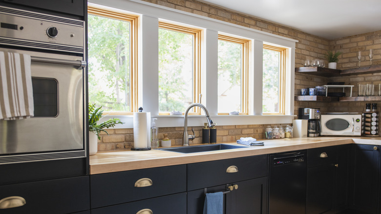 Kitchen with brick walls, dark cabinetry, and stainless steel appliances