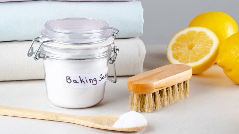 A pile of towels is placed by baking soda, a brush, and lemons