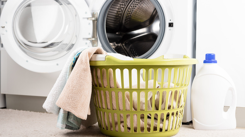 A basket of towels is plashed by a washer