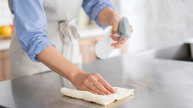 Woman spraying and wiping countertop