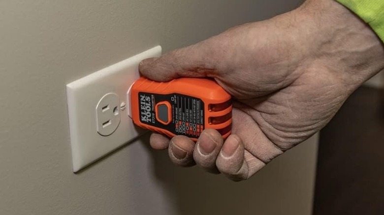 Person plugging the Klein Tools transmitter into an outlet