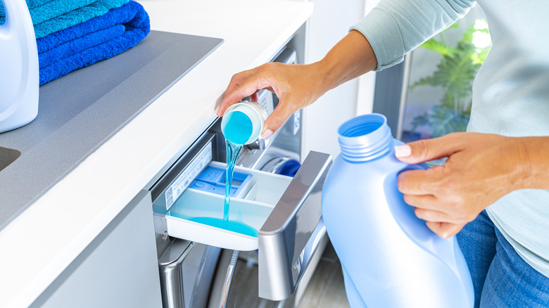 hands putting detergent in washer