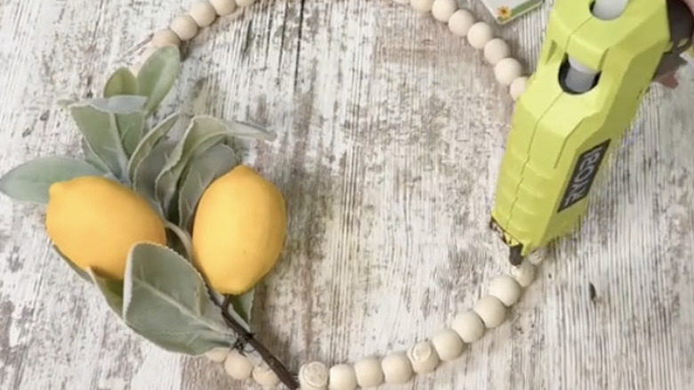 Gluing lemon and fauna sprigs to wreath