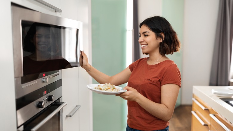 Woman putting food in microwave