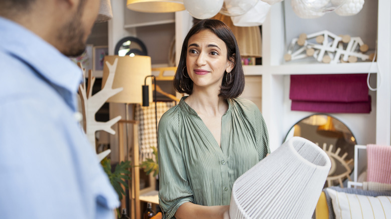 Woman shopping in store, holding unique lamp