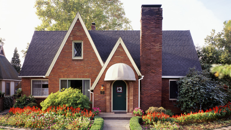 Flower beds are in front of a tidy brick home