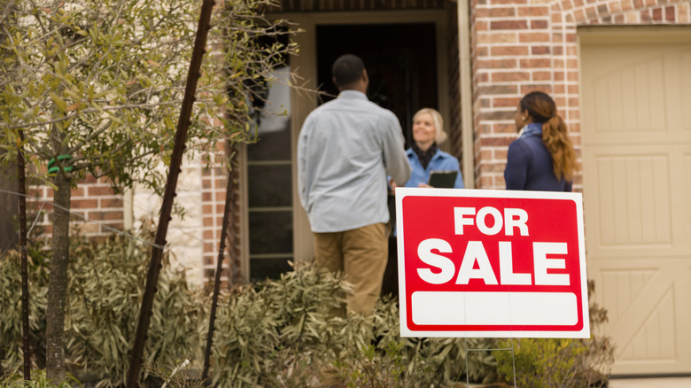 A "For Sale" sign is in front of a house