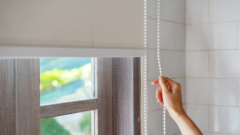 Person opening a window shade in their home