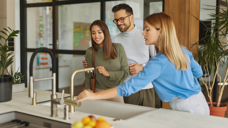 salesperson showing kitchen sink to couple