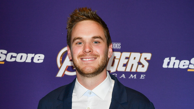 Mike Holmes Jr. smiling in front of a purple background