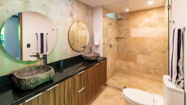 A modern bathroom with natural stone tile floors and walls