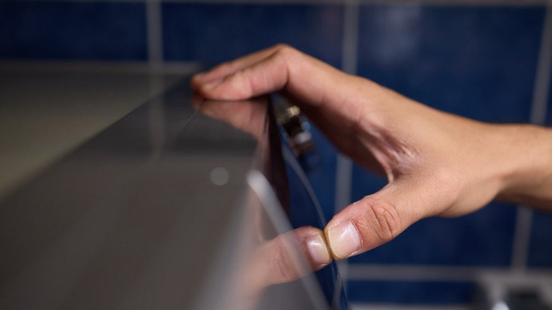 A person presses their fingers against a kitchen surface