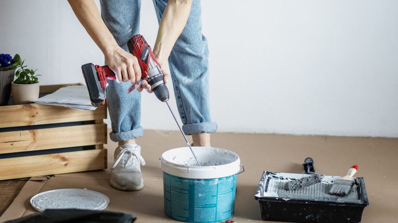 person mixing paint with drill