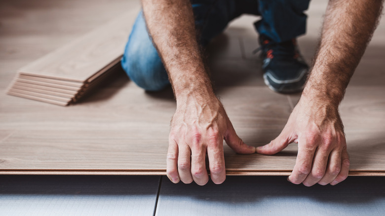 person piecing together floating floor