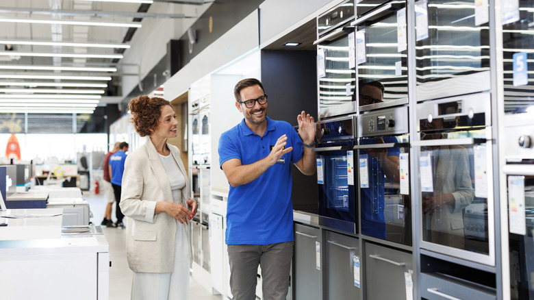 Employee showing woman appliances in store