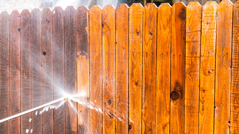 person washing wooden fence