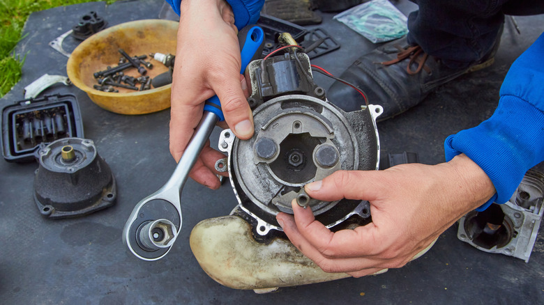 A person pulling apart a string trimmer showing a few of the parts